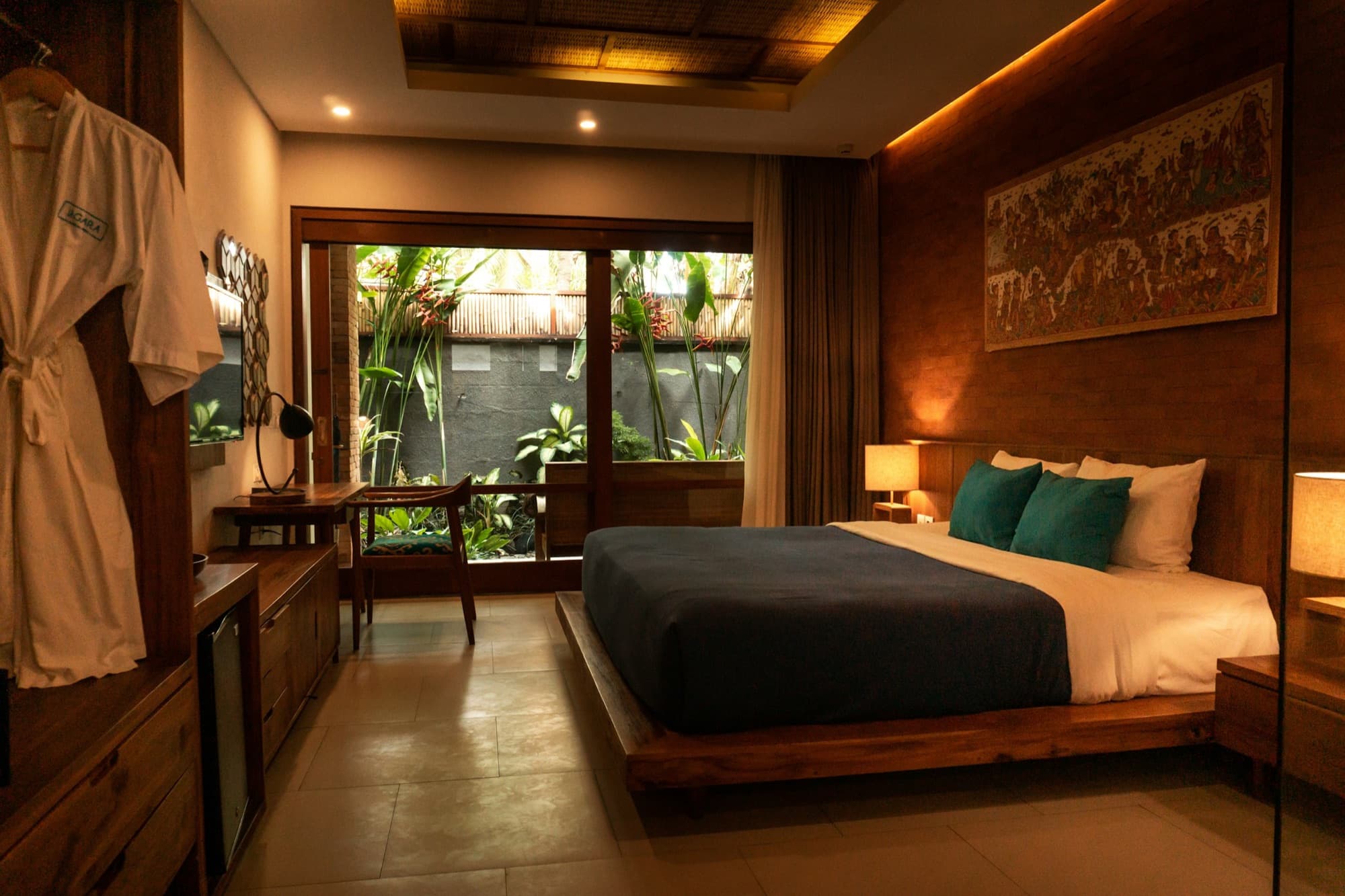 A warm hotel bedroom with a wooden bed and a view onto a private garden