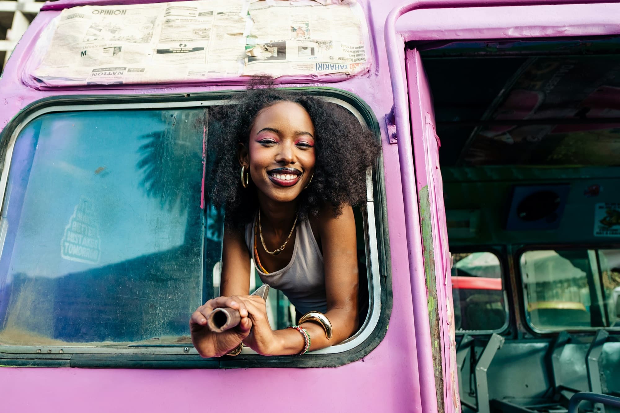 A smiling woman leaning out of a bus window on a trip