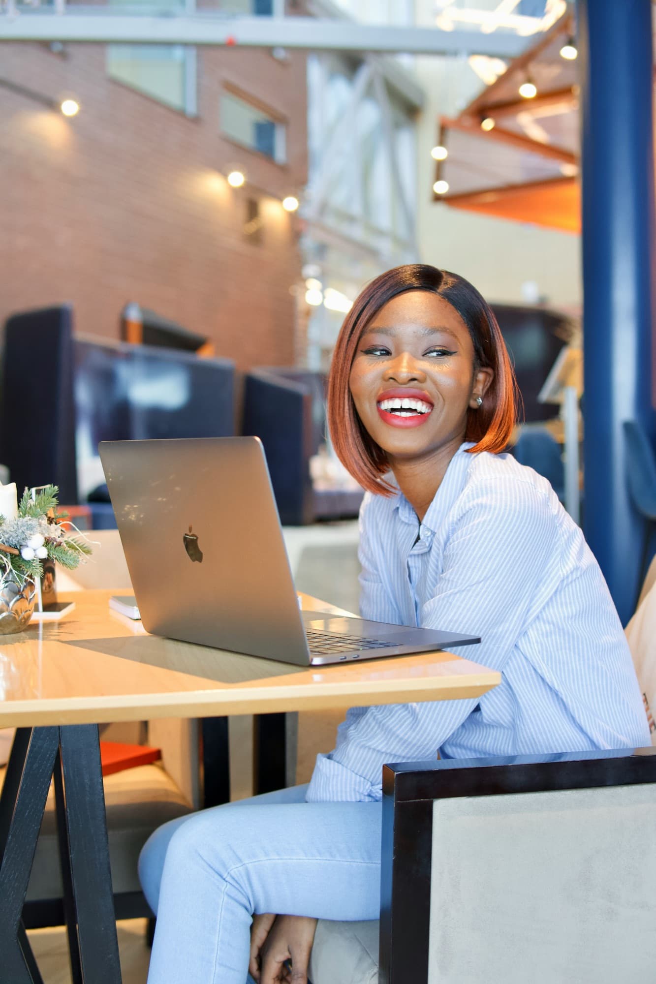 A smiling woman working on her laptop at a café table