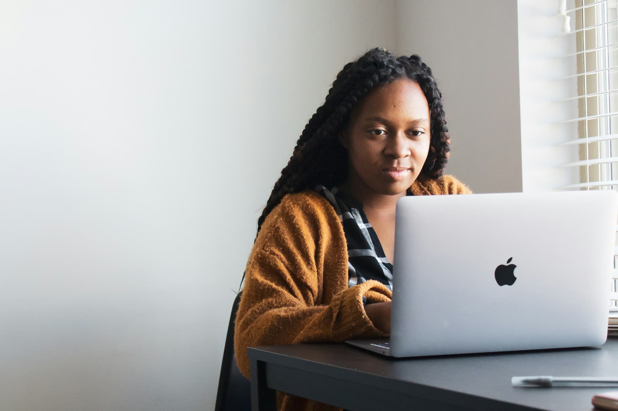 A woman with braids working on a laptop at a desk